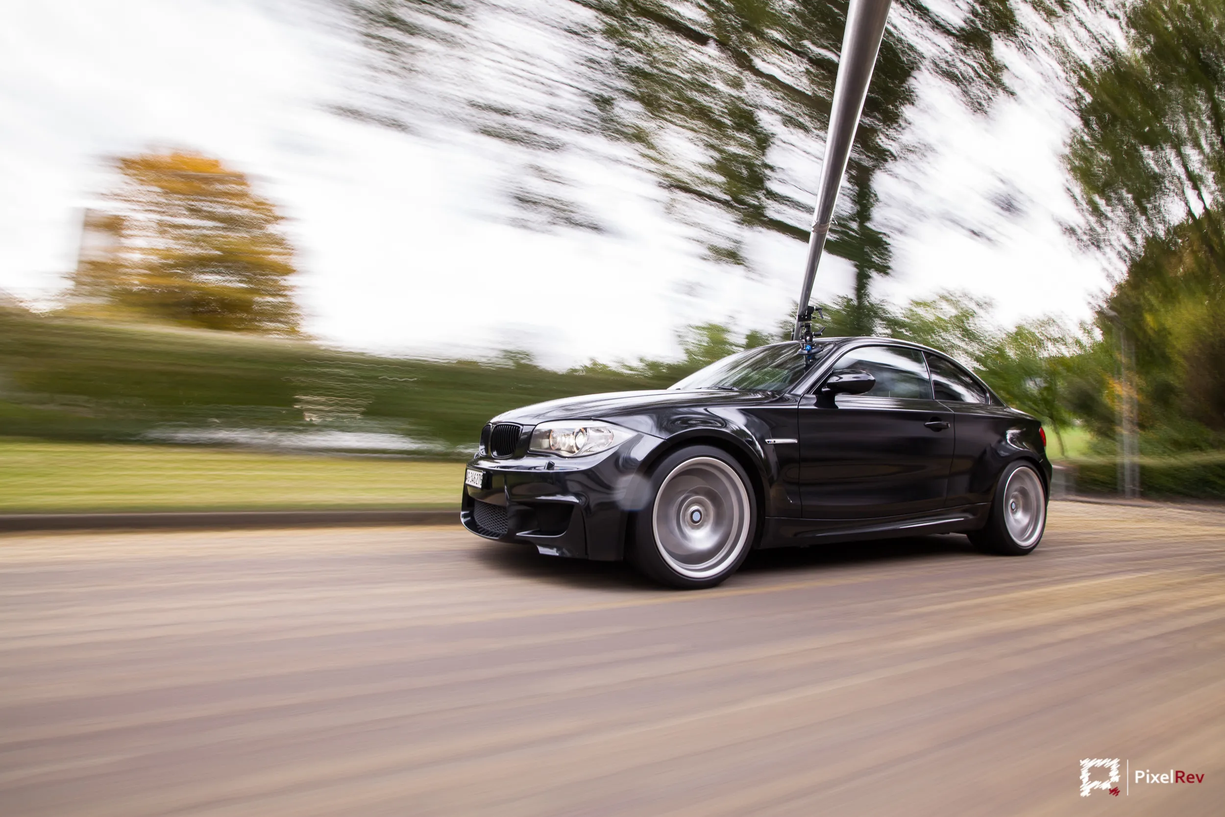 Schwarzes BMW 1M Coupé im Rig Shot, Bäume in Bewegungsunschärfe