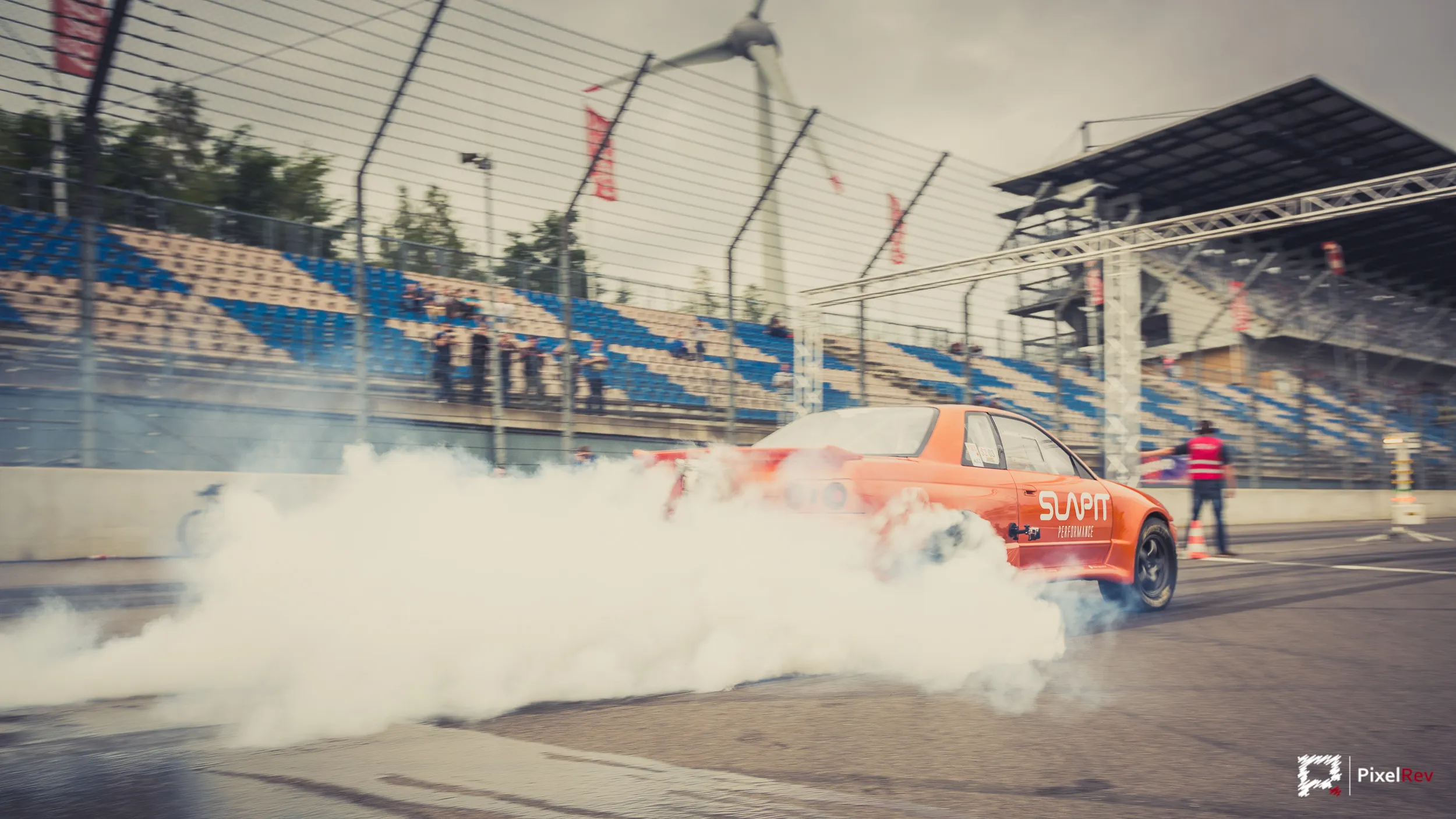 Orangefarbenes Fahrzeug beim Burnout vor der Tribüne am Lausitzring