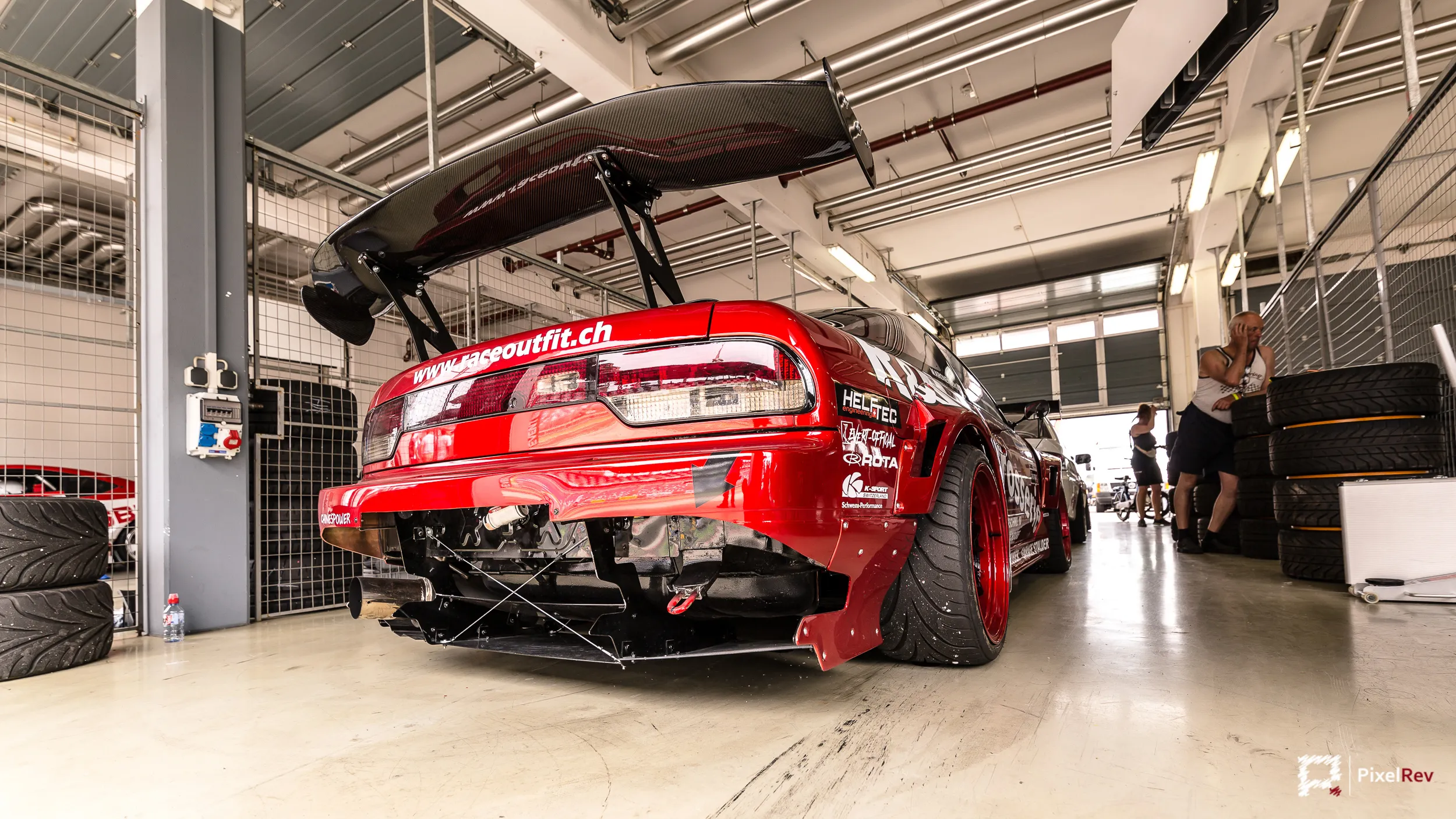 Rotes Driftfahrzeug mit großem Heckflügel in der Box