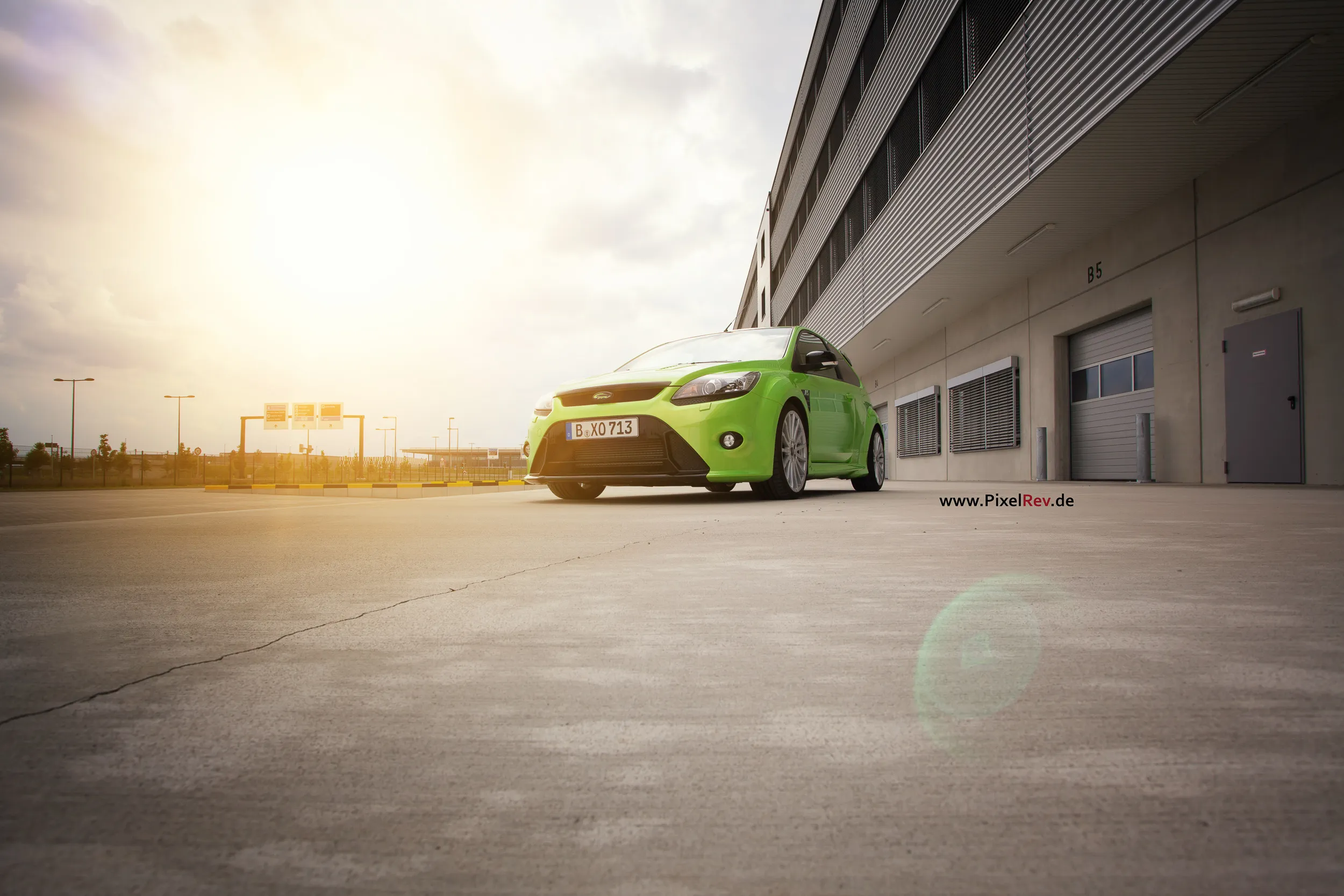 Grüner Ford Focus RS im Gegenlicht vor einem Gebäude am Flughafen BER