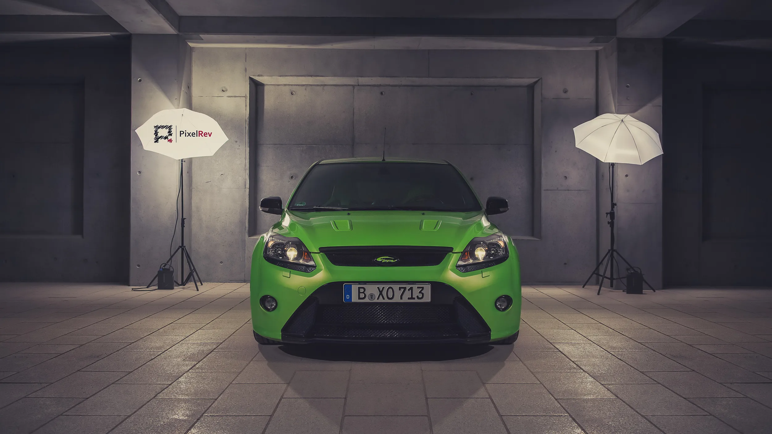 Grüner Ford Focus RS frontal in einer Betonhalle mit zwei Schirmblitzen