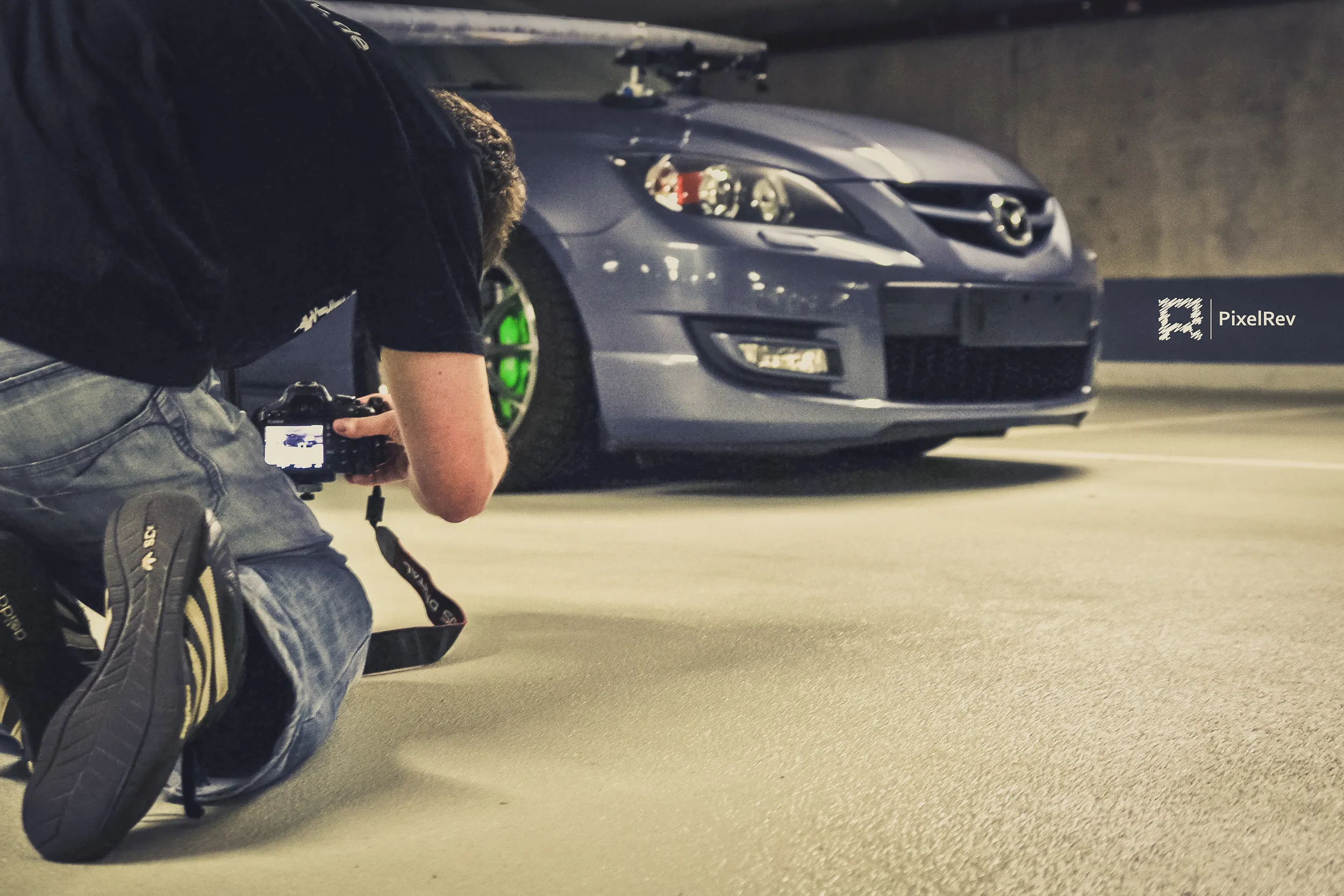 Fotograf kniet vor einem grauen Mazda 3 MPS in einer Tiefgarage