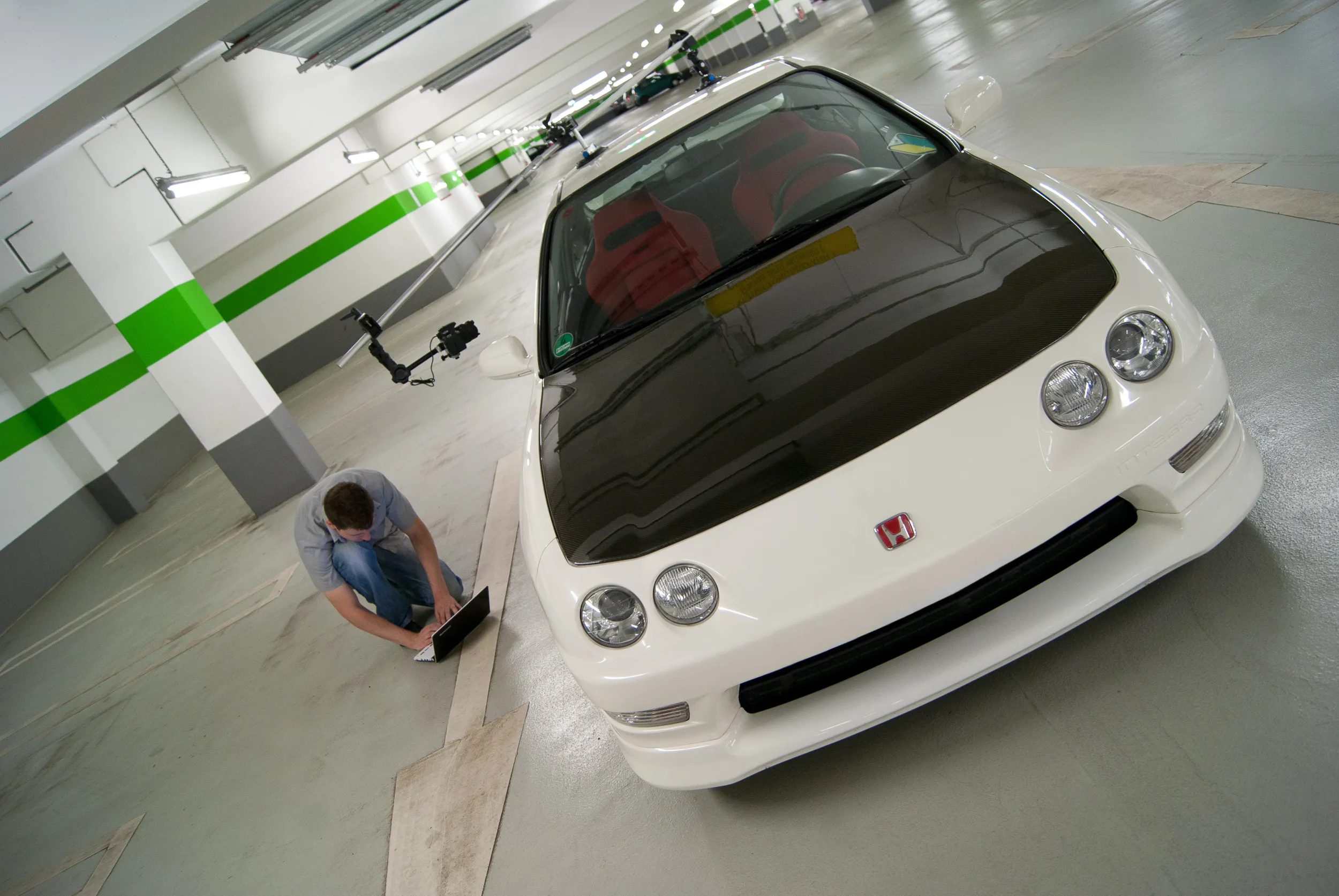 Weißer Honda Integra Type R DC2 mit Kamera-Rig in einem Parkhaus, daneben der Fotograf
