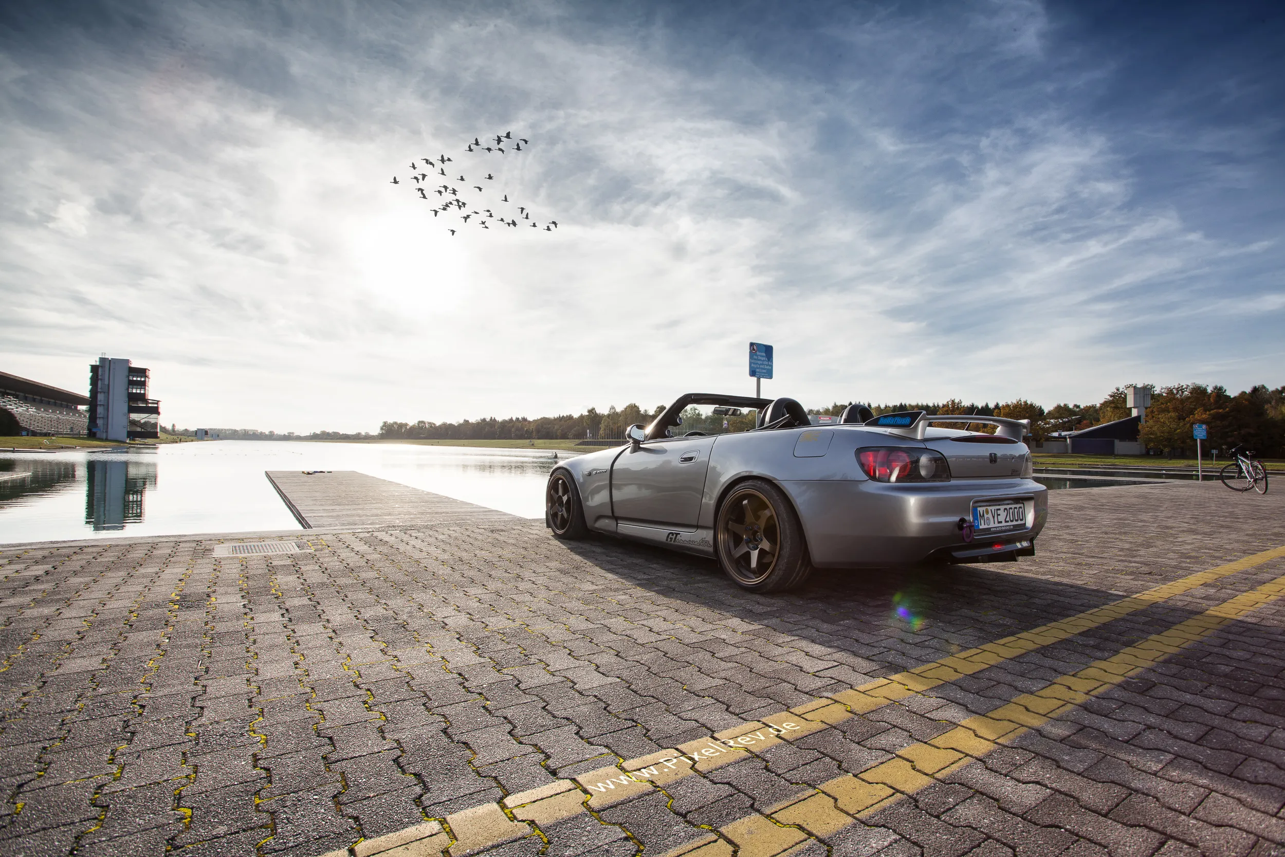 Silberner Honda S2000 Roadster am Wasser einer Regattastrecke bei München