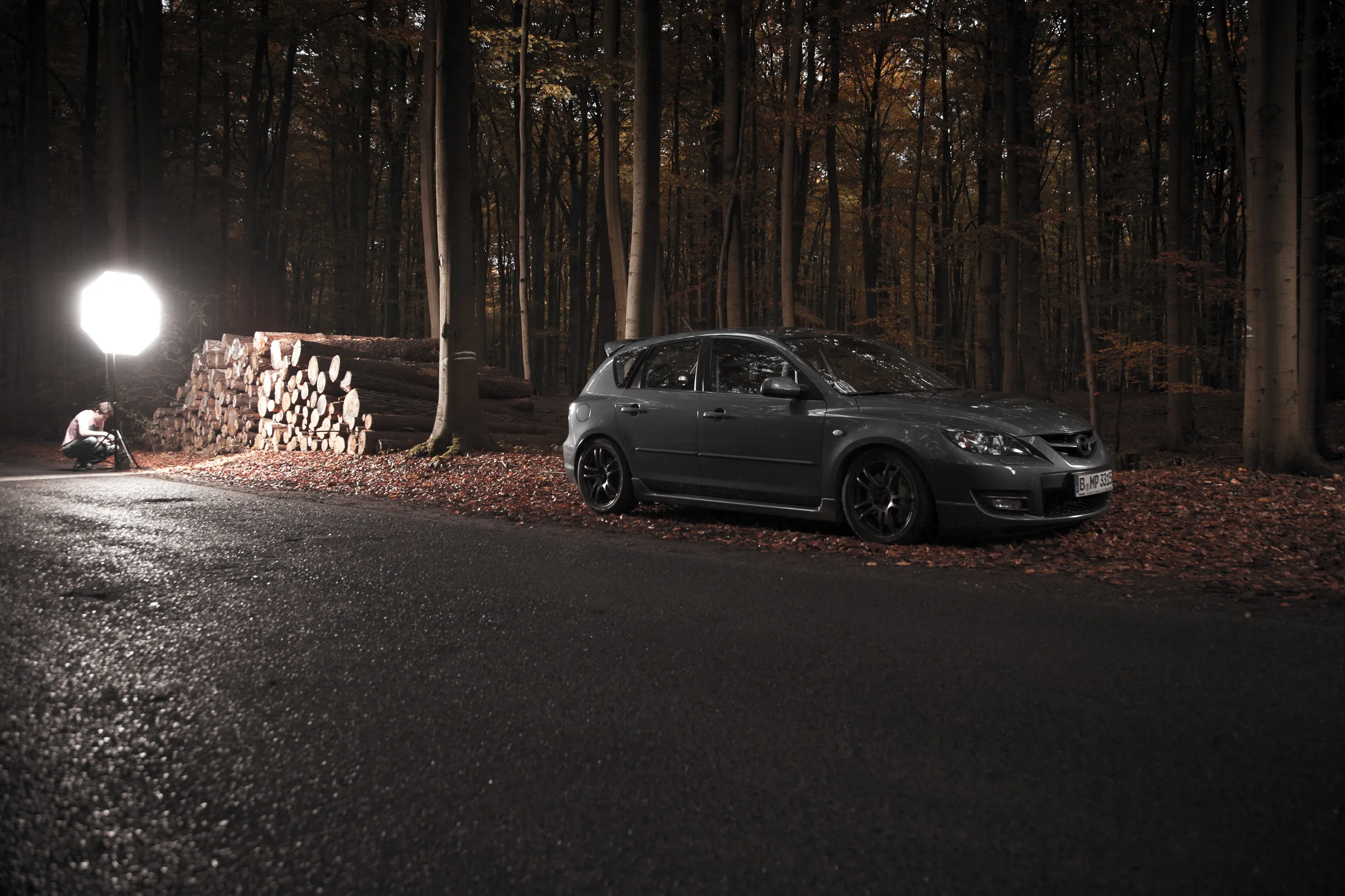 Grauer Mazda 3 MPS im herbstlichen Wald, seitlich mit Softbox ausgeleuchtet