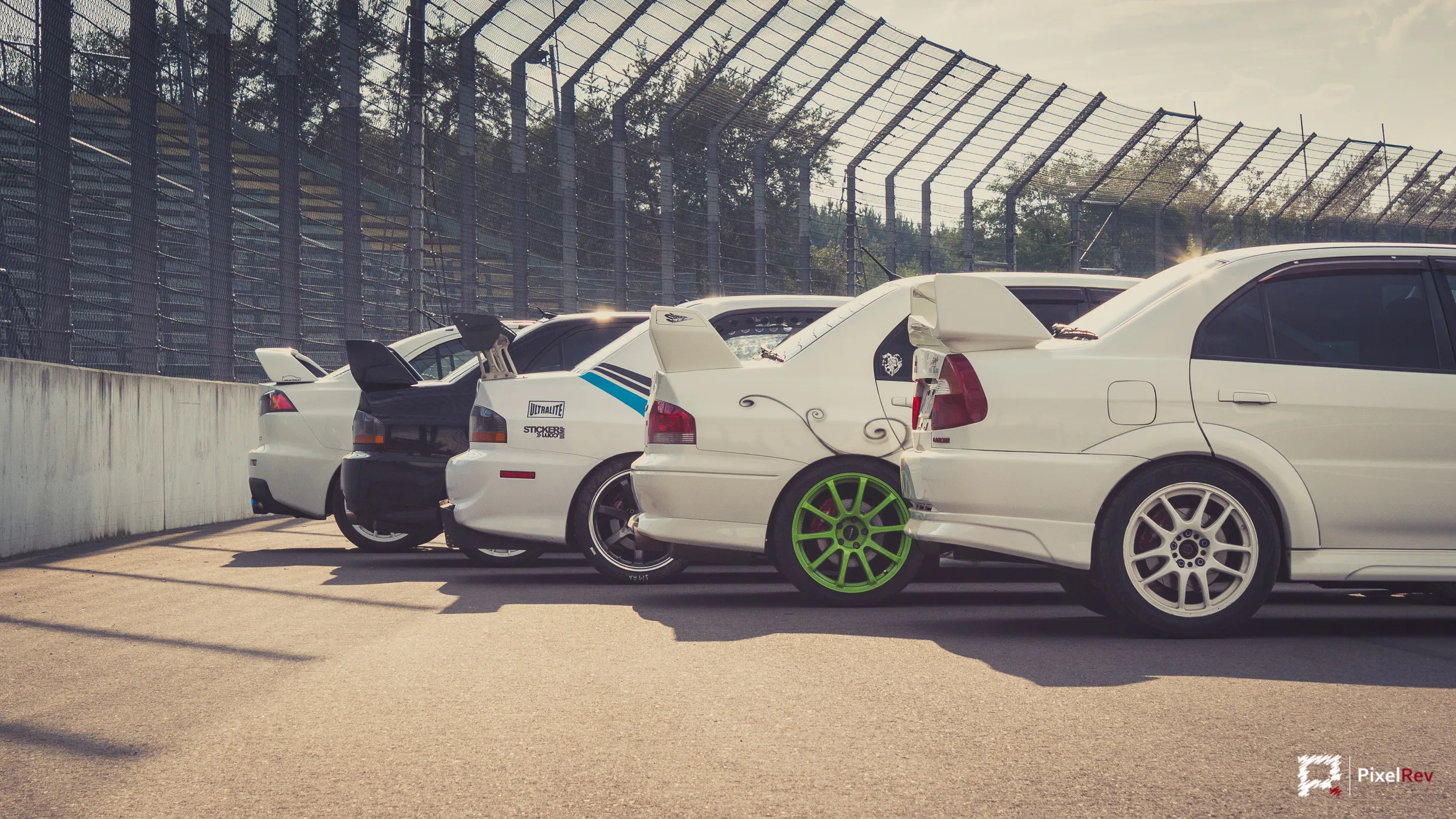 Hecks mehrerer Mitsubishi Lancer Evolution, einer mit grünen Felgen