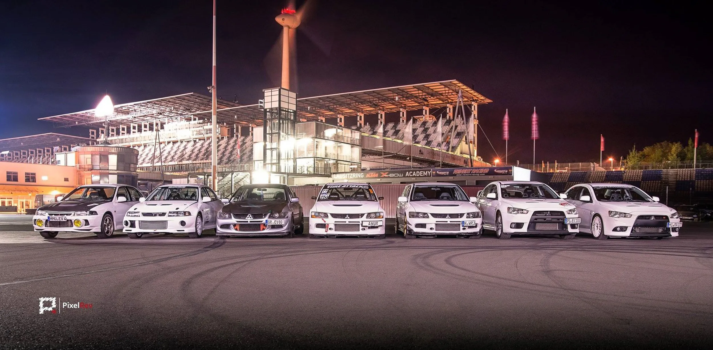 Reihe von Mitsubishi Lancer Evolution bei Nacht vor der Tribüne am Lausitzring