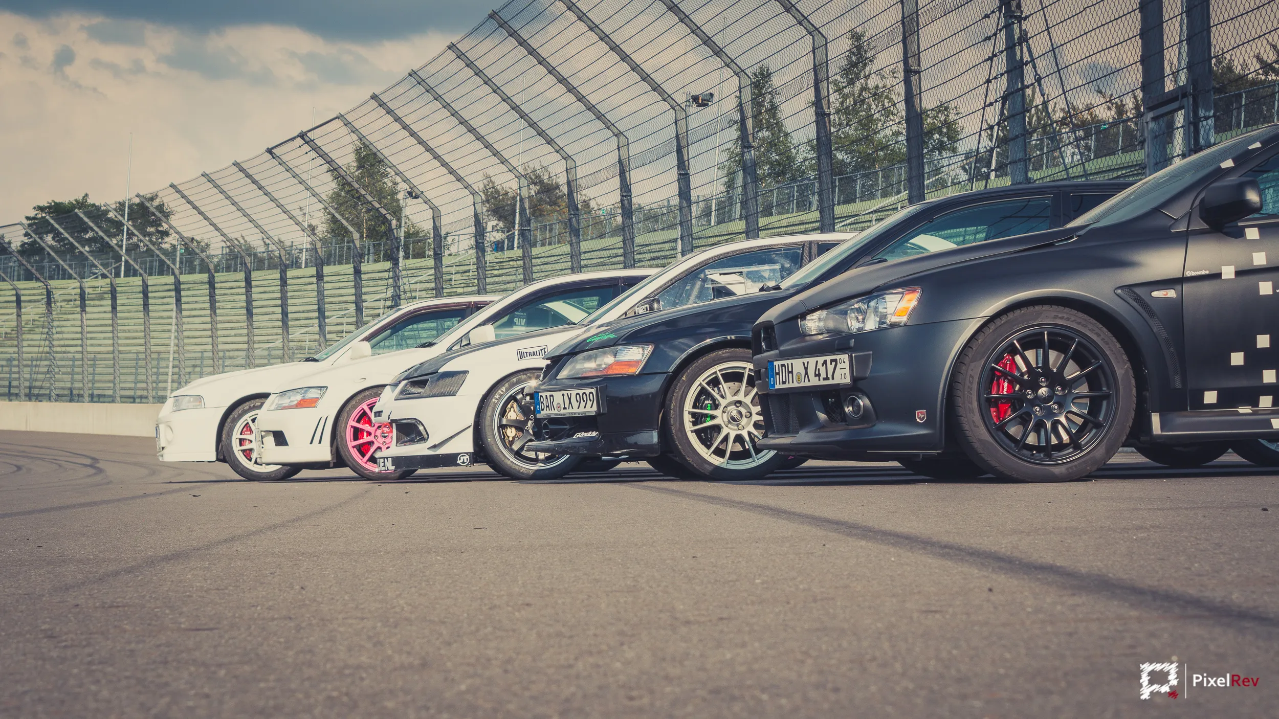 Front eines schwarzen Mitsubishi Lancer Evolution X, dahinter weitere Evos