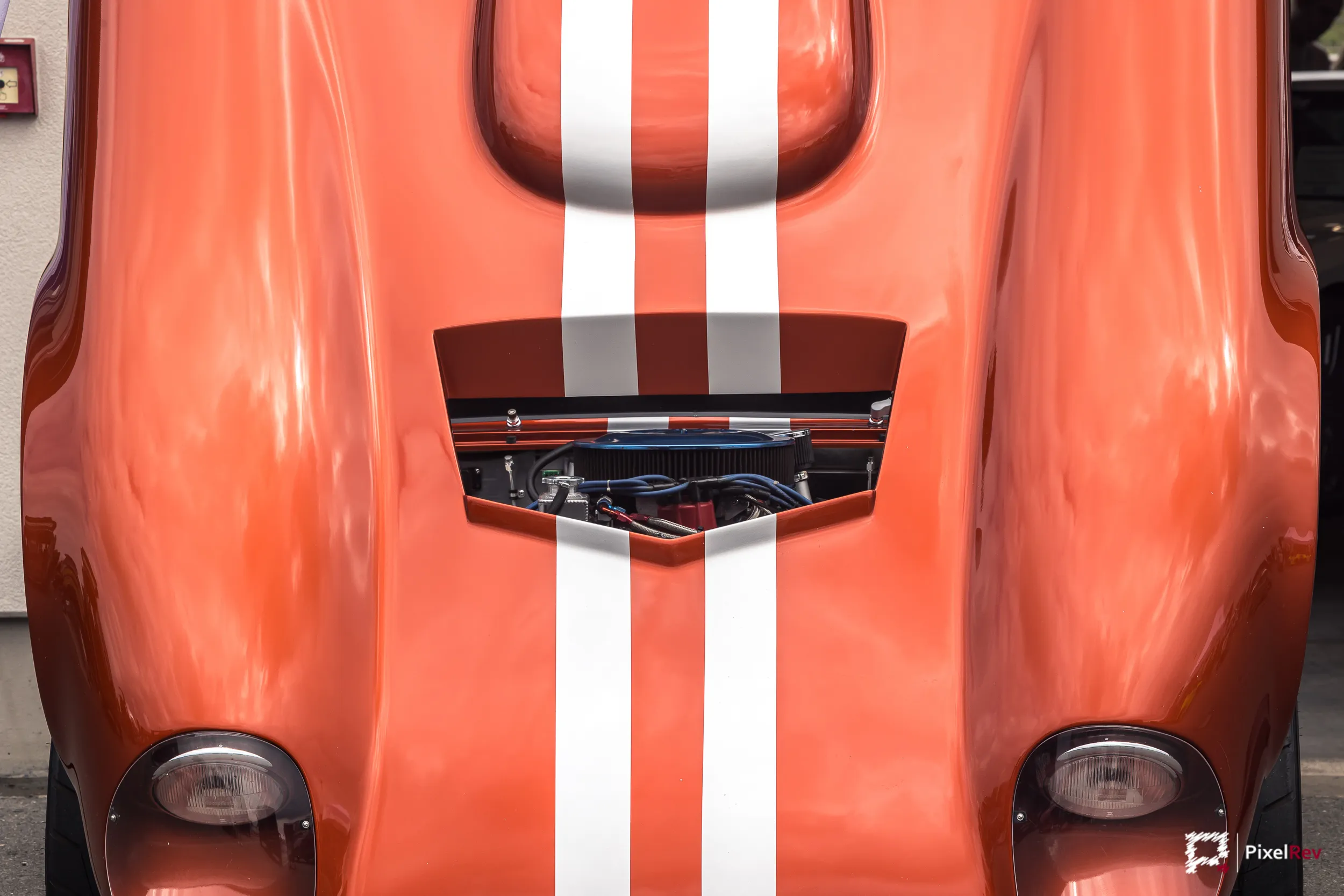 Orangefarbene Motorhaube mit weißen Rennstreifen und Lufteinlass, Detailaufnahme