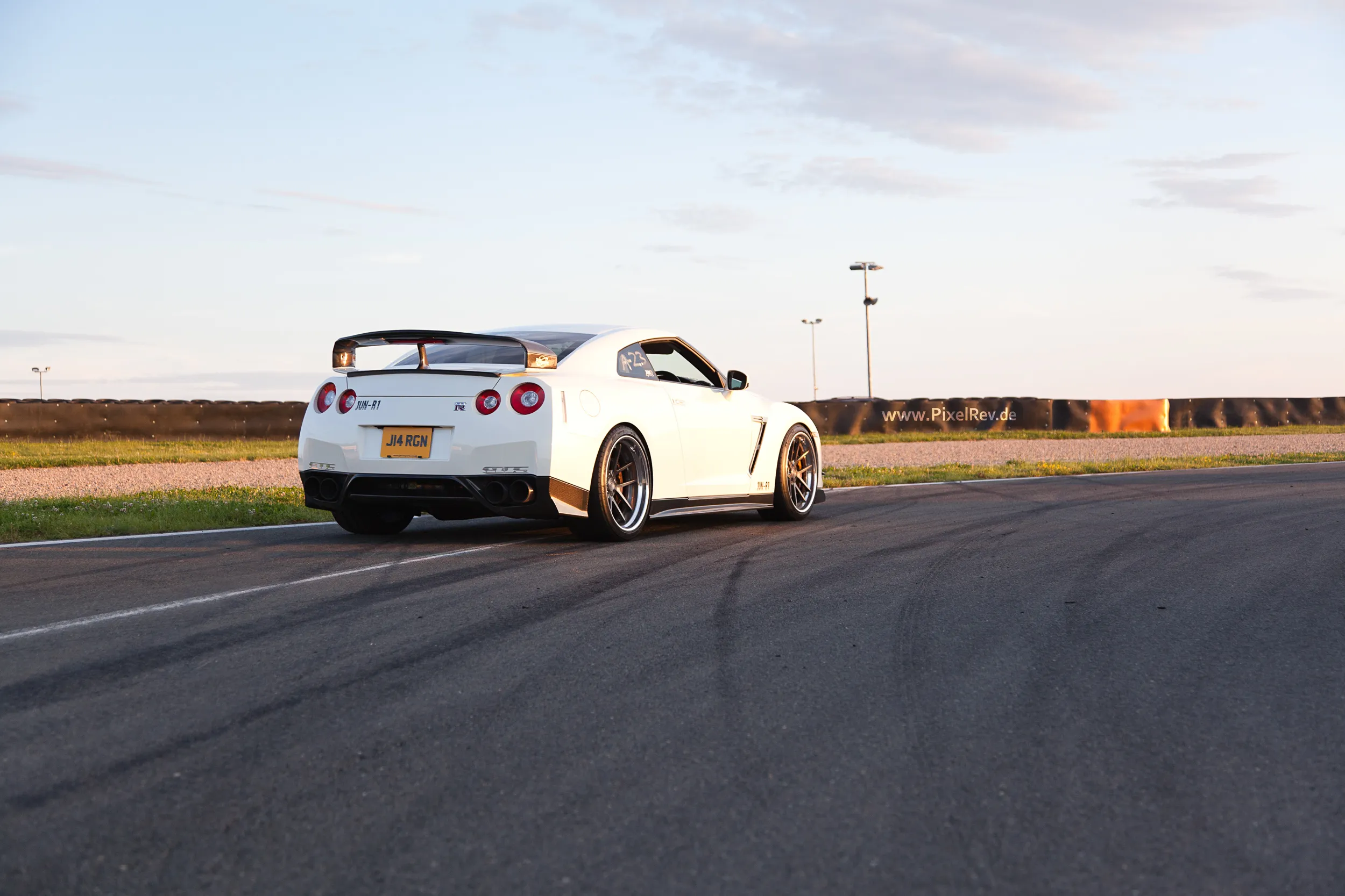 Weißer Nissan GT-R R35 im Abendlicht auf der Rennstrecke