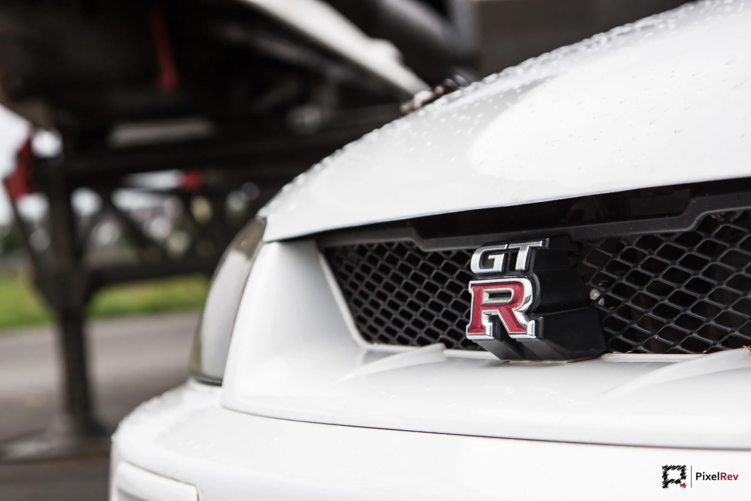 GT-R-Emblem am Kühlergrill eines weißen Nissan Skyline R33, Detailaufnahme