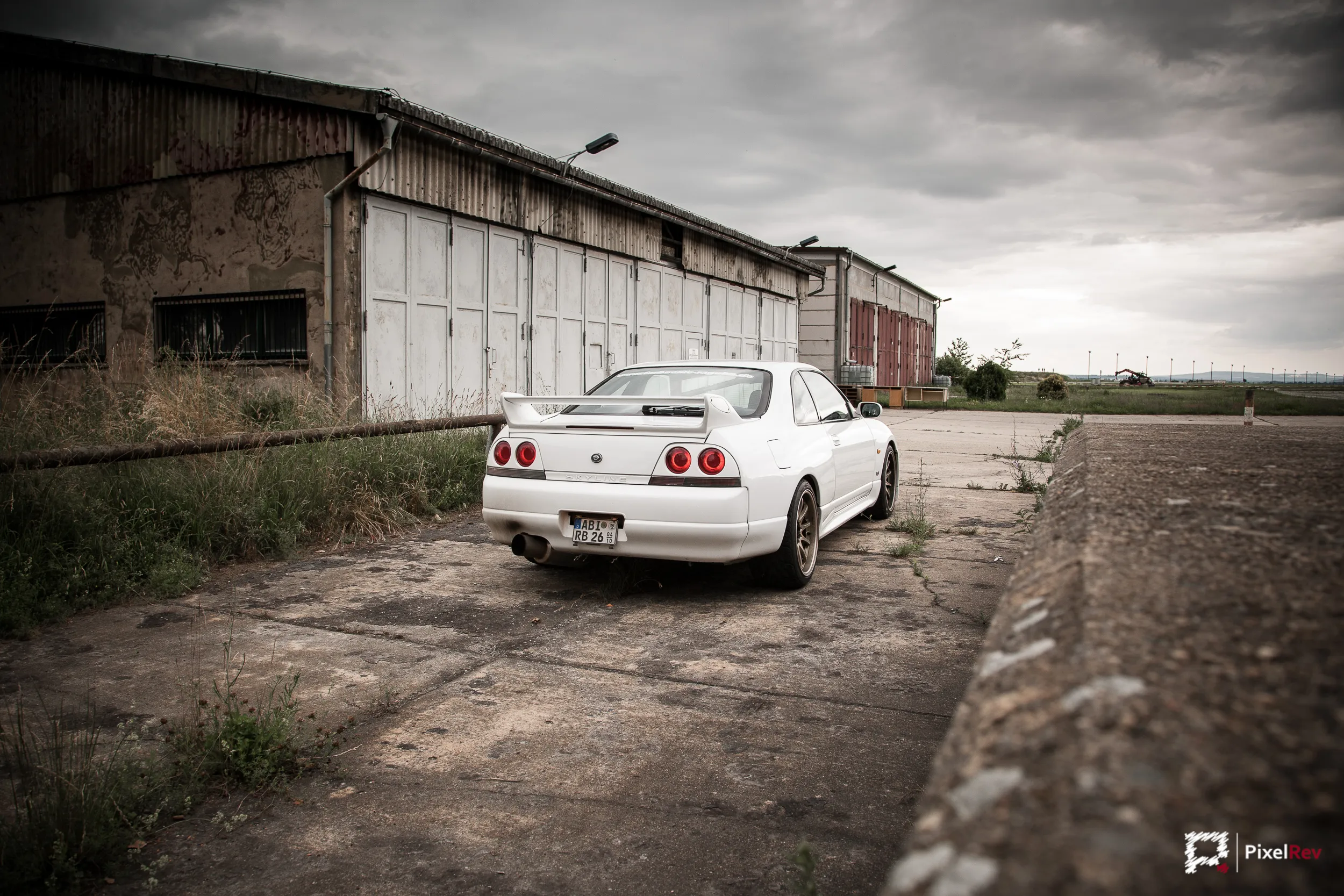 Heck des Nissan Skyline R33 GT-R vor einem verfallenen Hangar