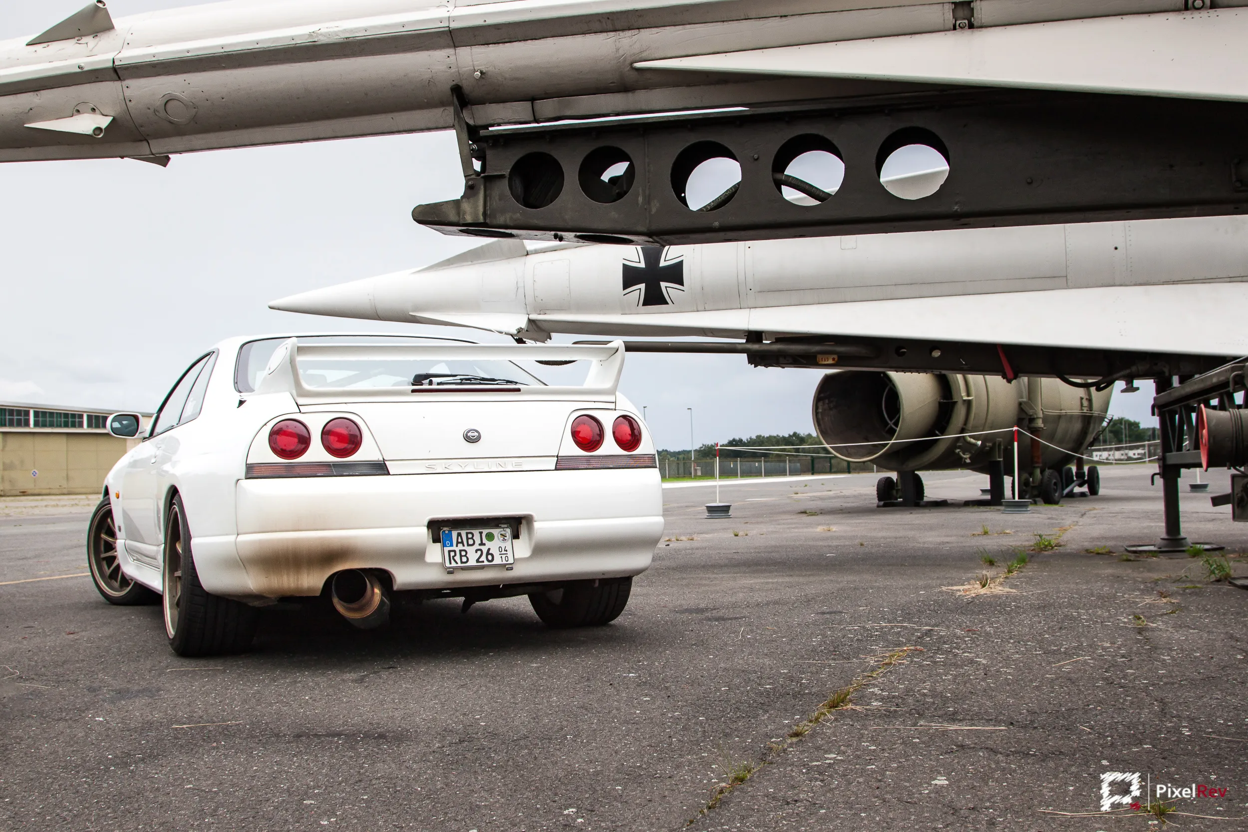 Heck eines weißen Nissan Skyline R33 GT-R unter ausgestellten Raketen