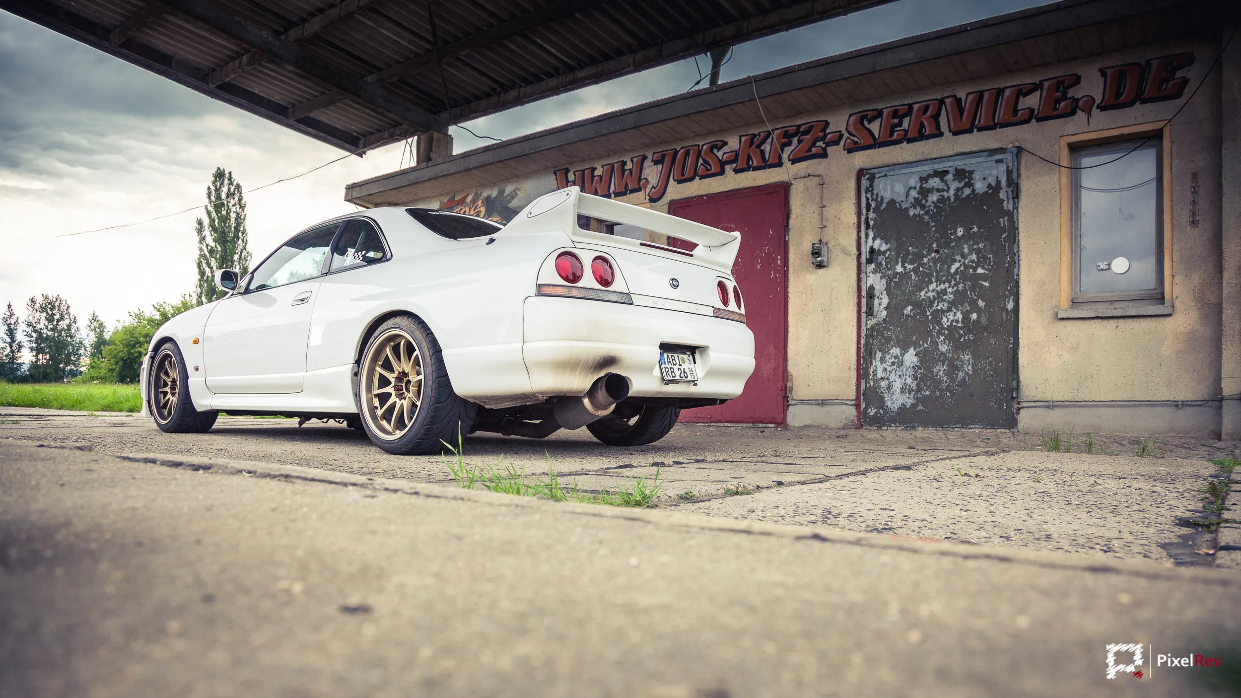 Heck eines weißen Nissan Skyline R33 GT-R mit goldenen Felgen