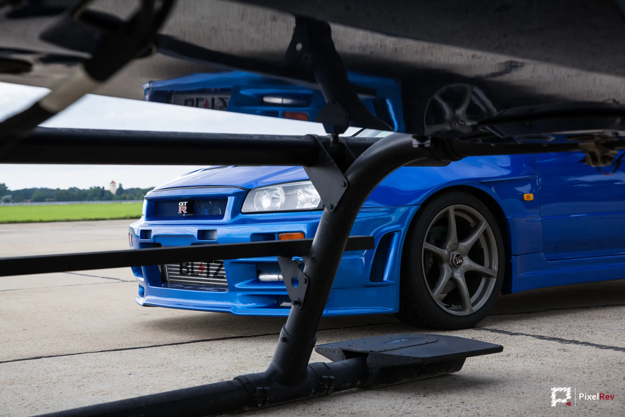 Front des Nissan Skyline R34 GT-R zwischen den Kufen eines Hubschraubers
