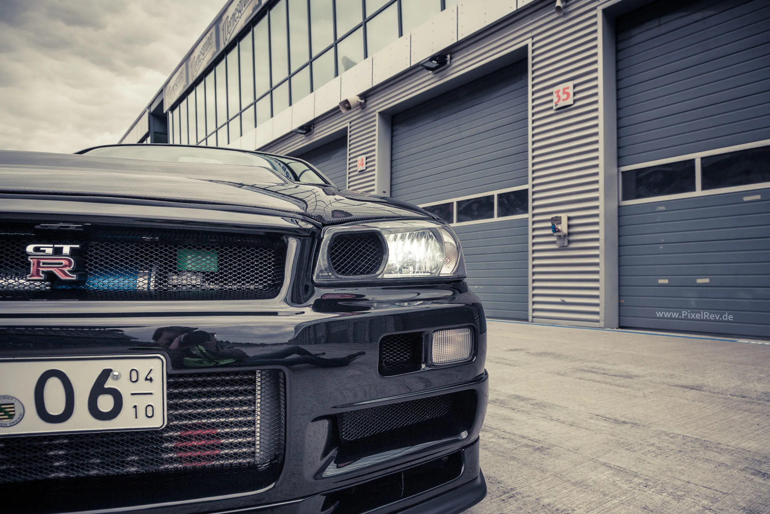Front des Nissan Skyline R34 GT-R Nismo Omori S1 vor den Boxen