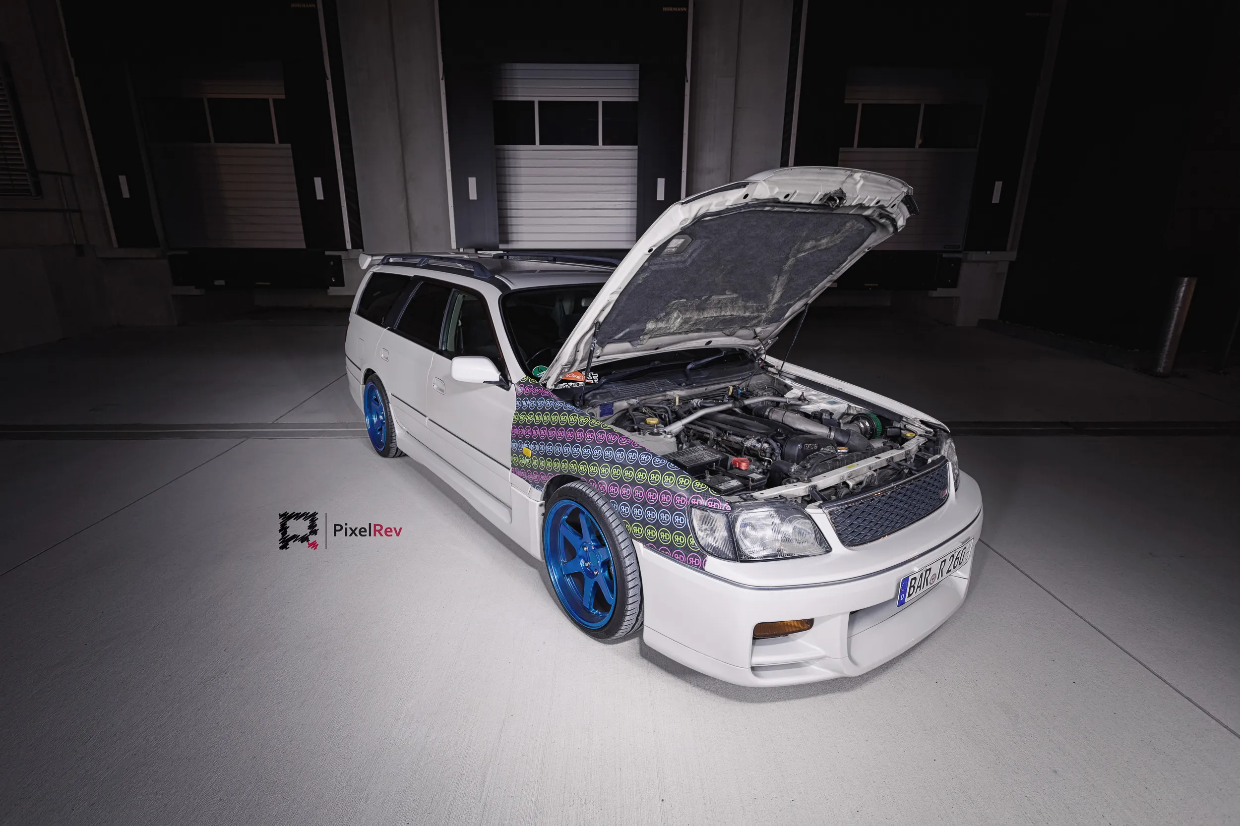 Nissan Stagea mit geöffneter Motorhaube vor Ladetoren