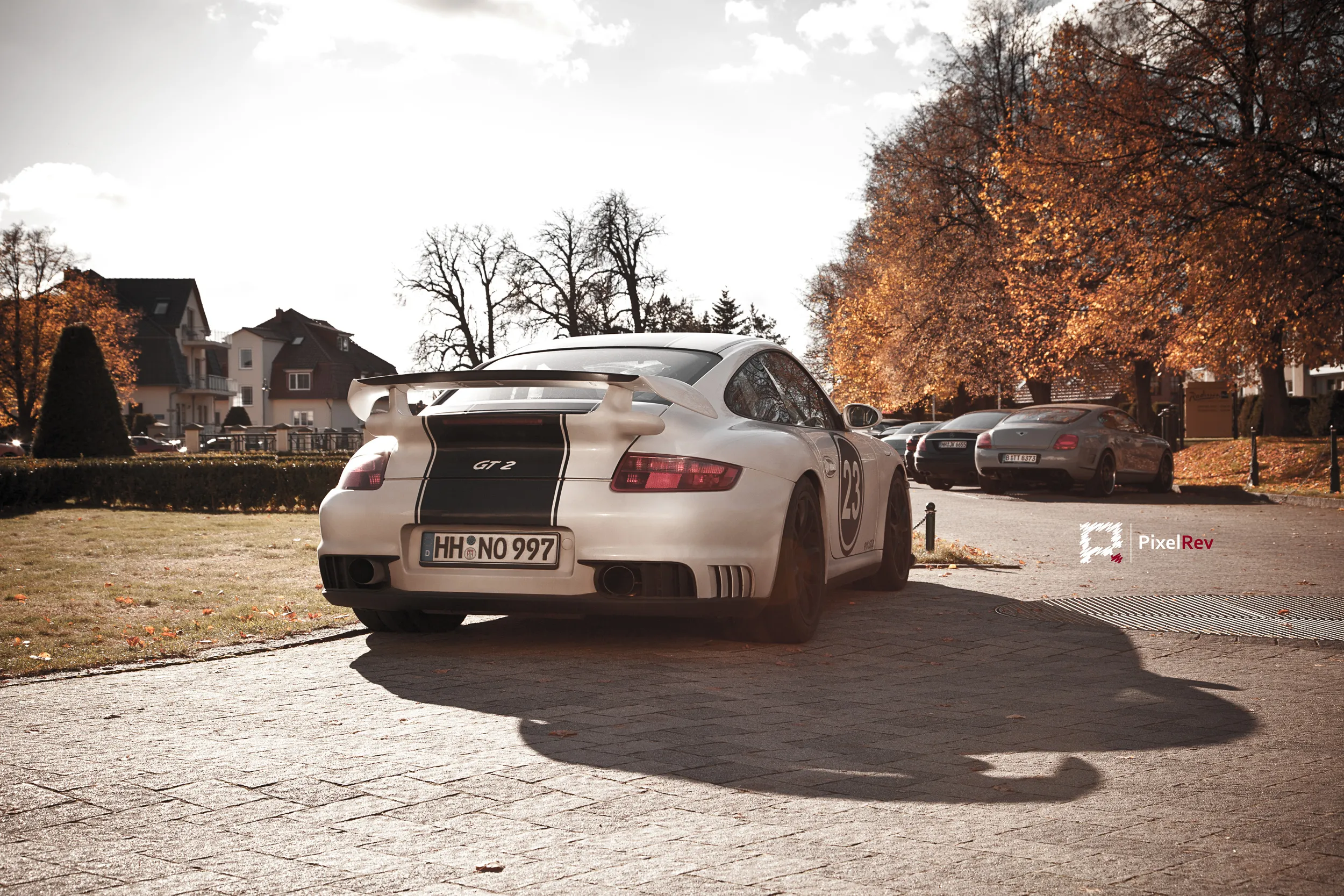 Weißer Porsche 911 von hinten auf einem Platz mit Herbstbäumen