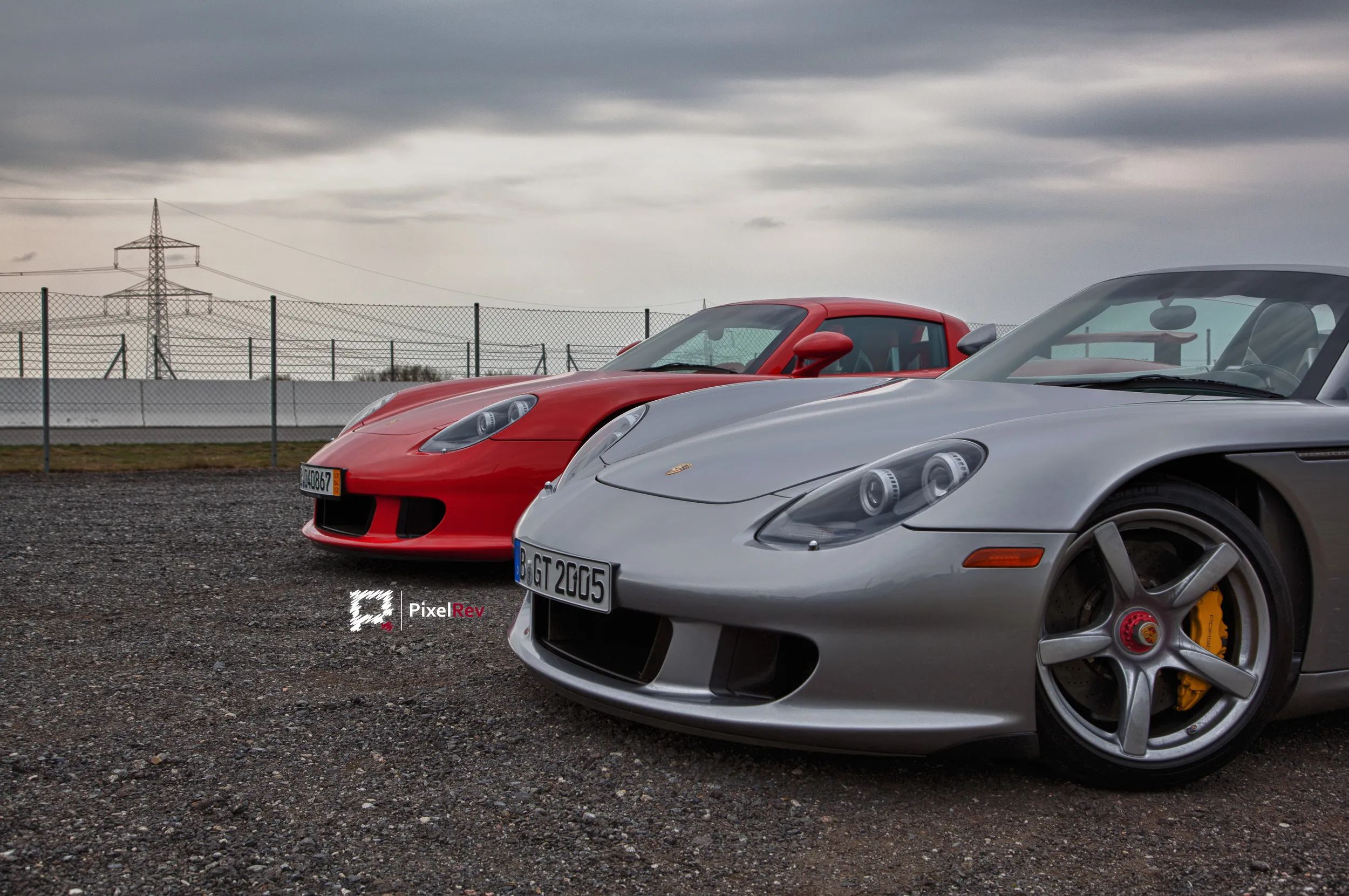 Zwei Porsche Carrera GT in Rot und Silber, Front des silbernen Wagens im Vordergrund