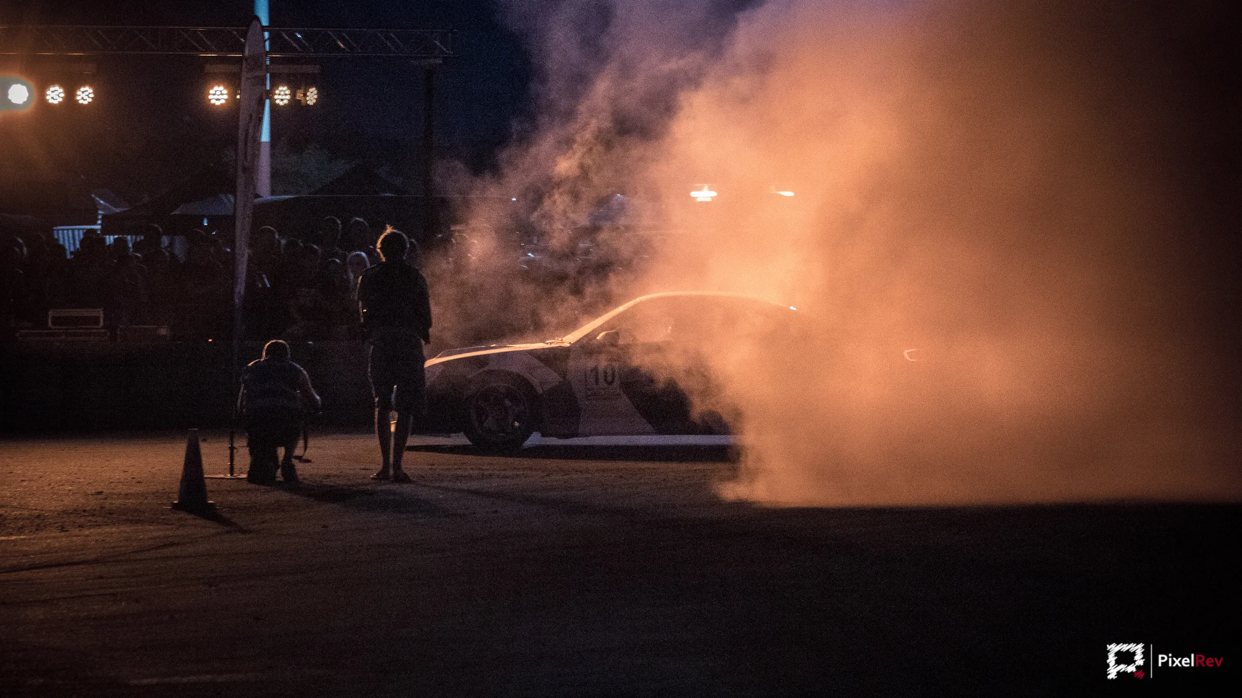 Fotografen im angestrahlten Reifenqualm am Rand der Driftstrecke bei Nacht