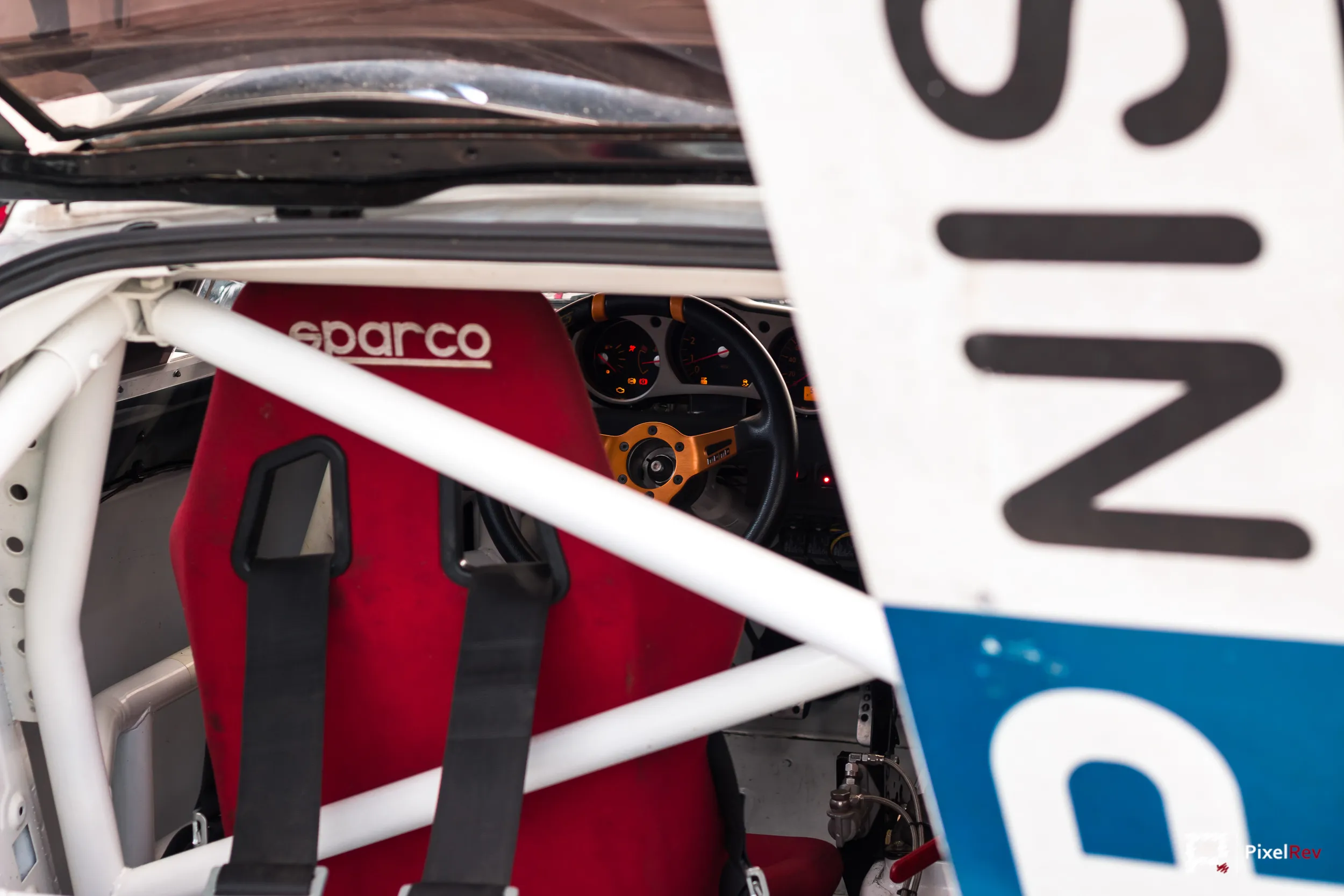Roter Sparco-Schalensitz hinter dem Überrollkäfig eines Rennwagens