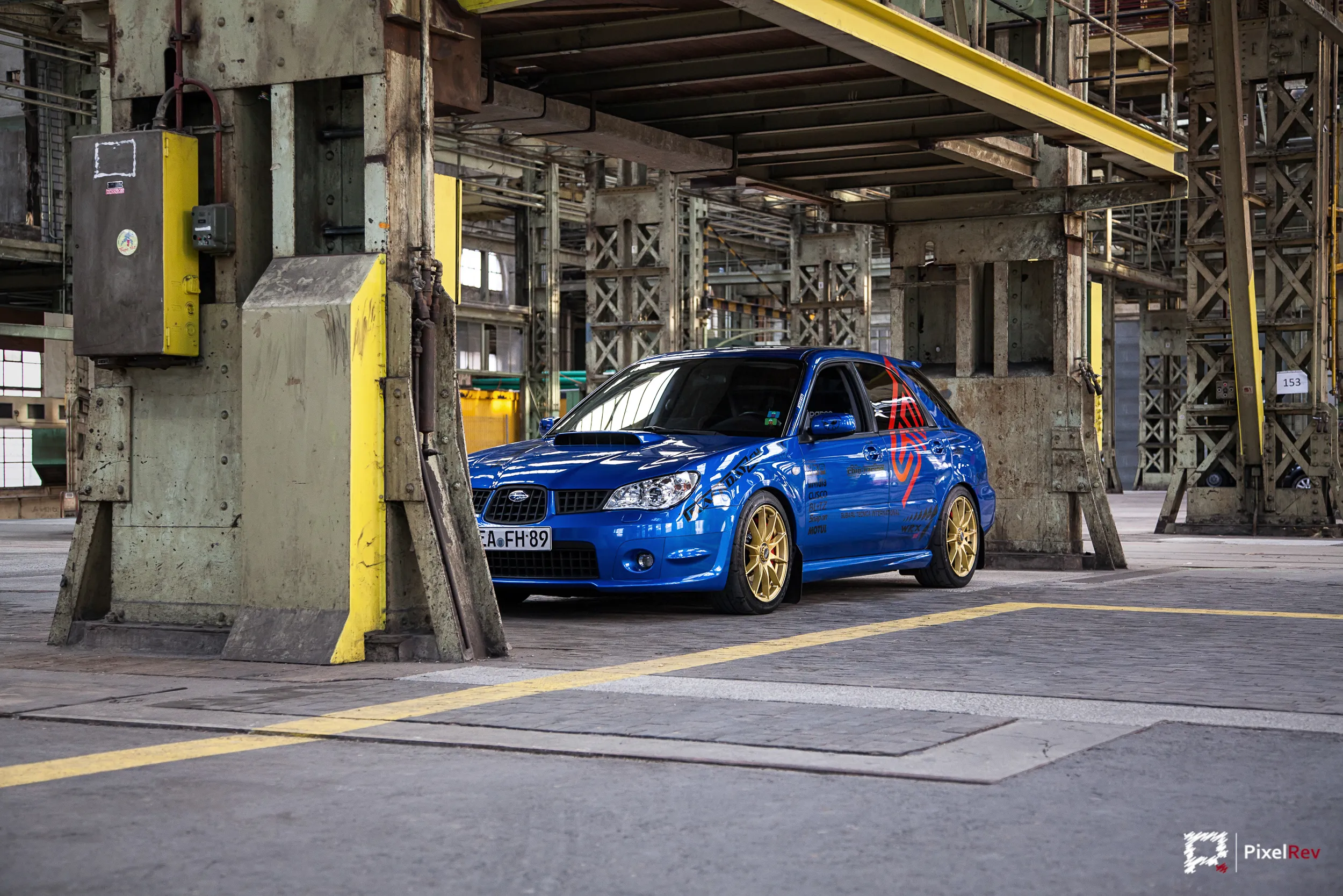 Blauer Subaru Impreza WRX STI mit goldenen Felgen in einer alten Industriehalle
