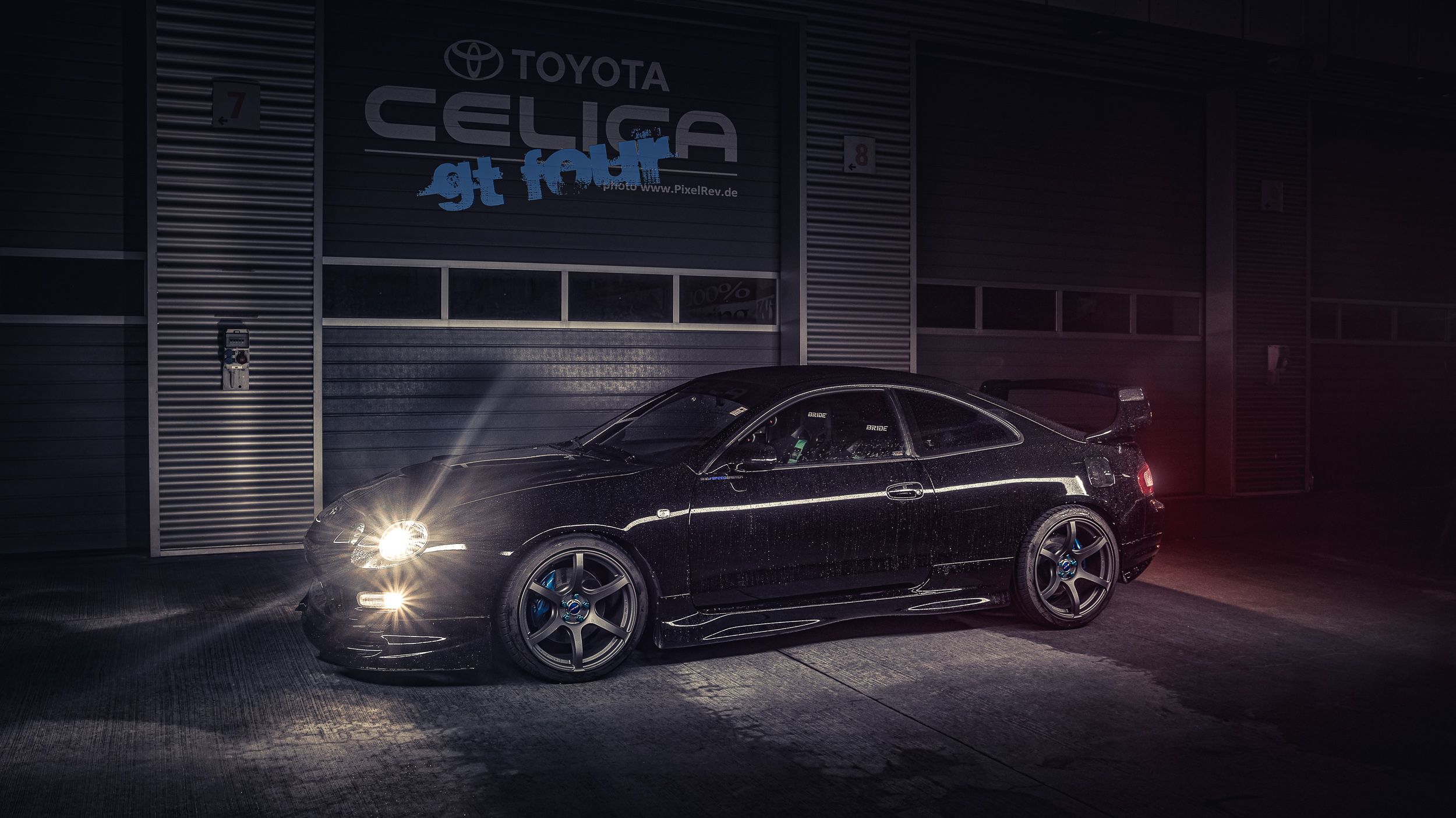 Schwarze Toyota Celica GT-Four mit Scheinwerferlicht vor einer Box mit Celica-Schriftzug