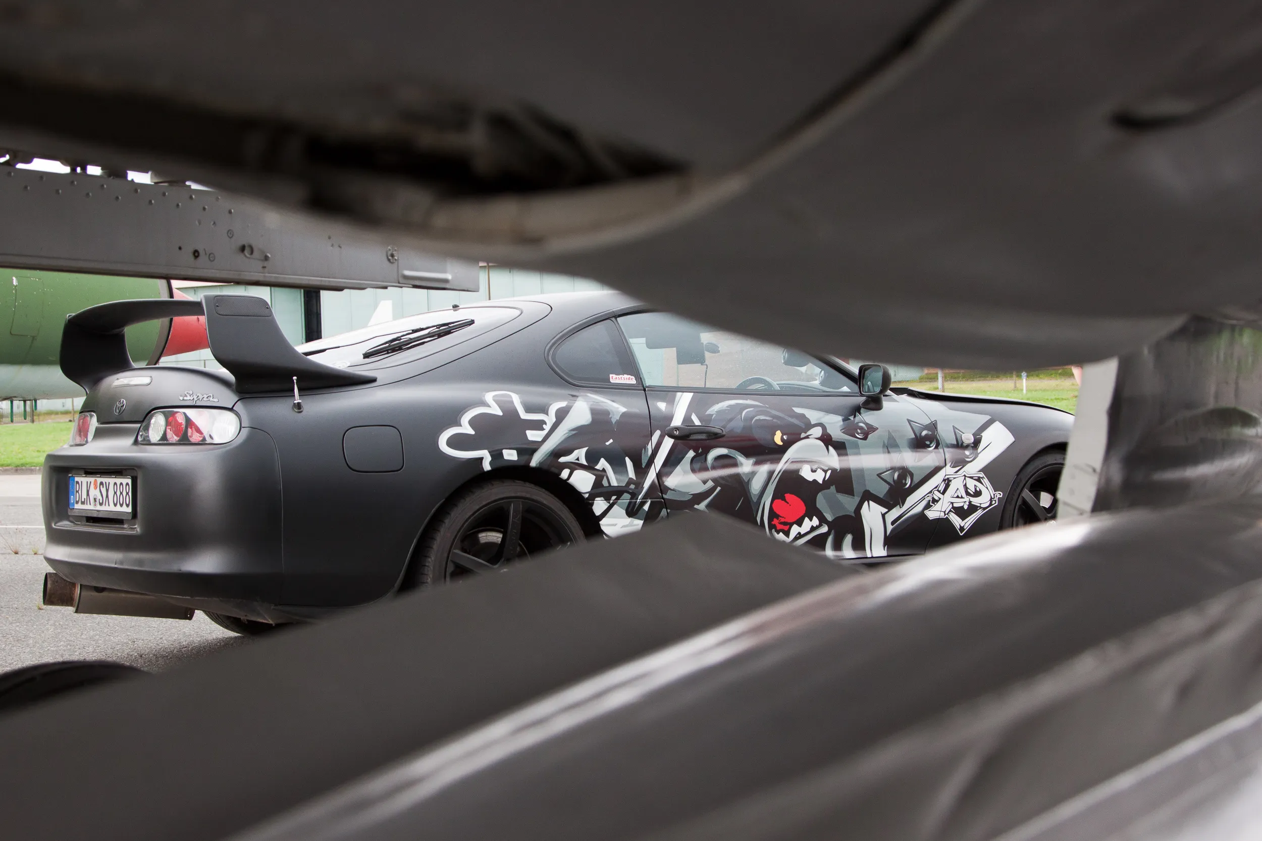 Folierter Toyota Supra, fotografiert unter dem Rumpf eines Kampfflugzeugs in Berlin-Gatow