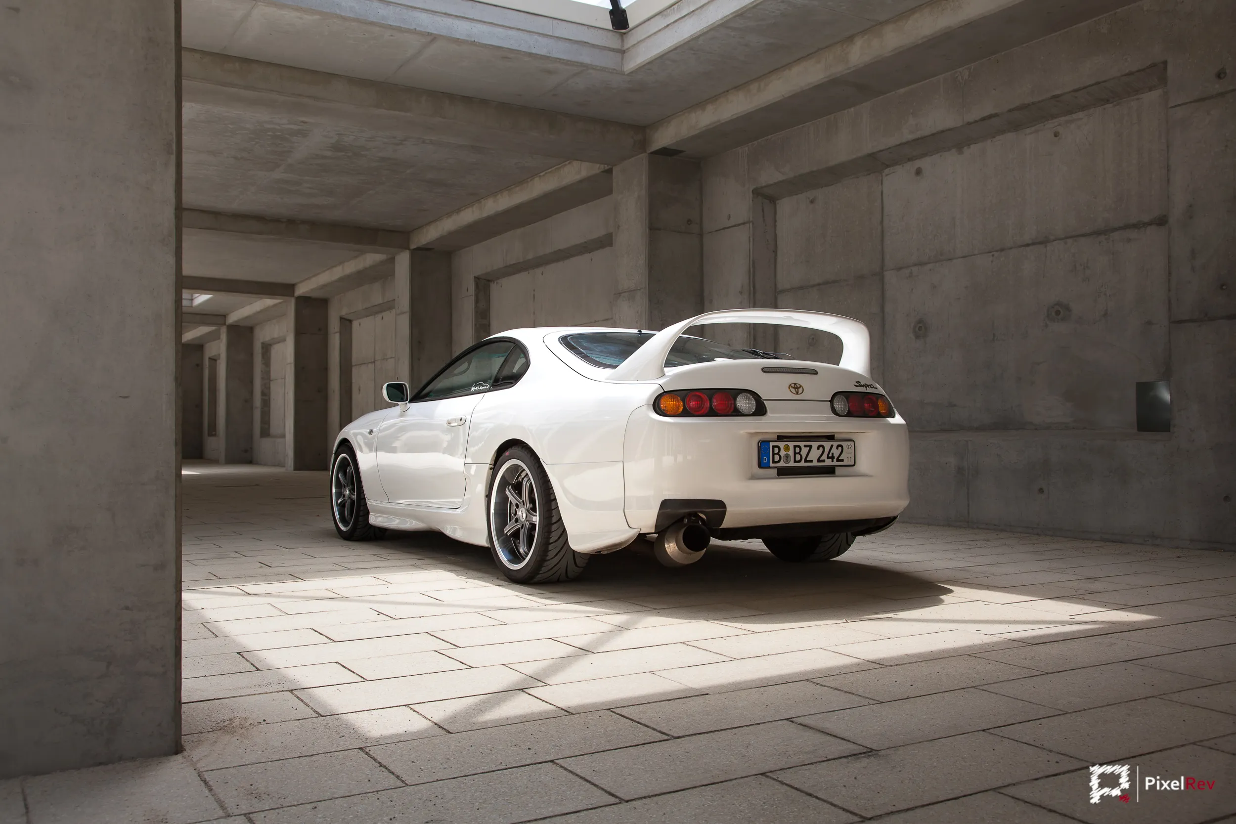 Weißer Toyota Supra von hinten in einer Betonhalle mit Lichteinfall