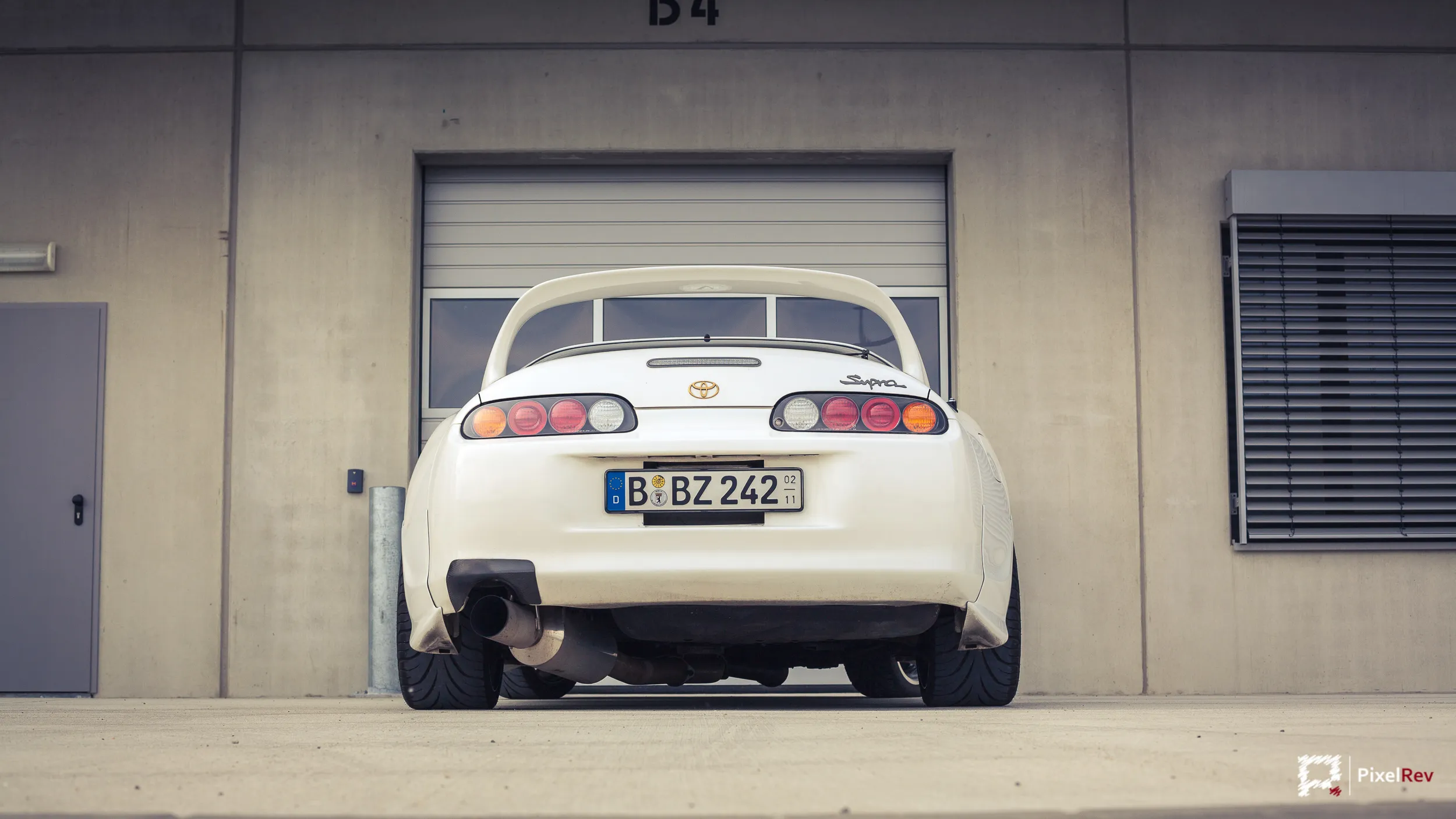Heck eines weißen Toyota Supra vor einem Rolltor