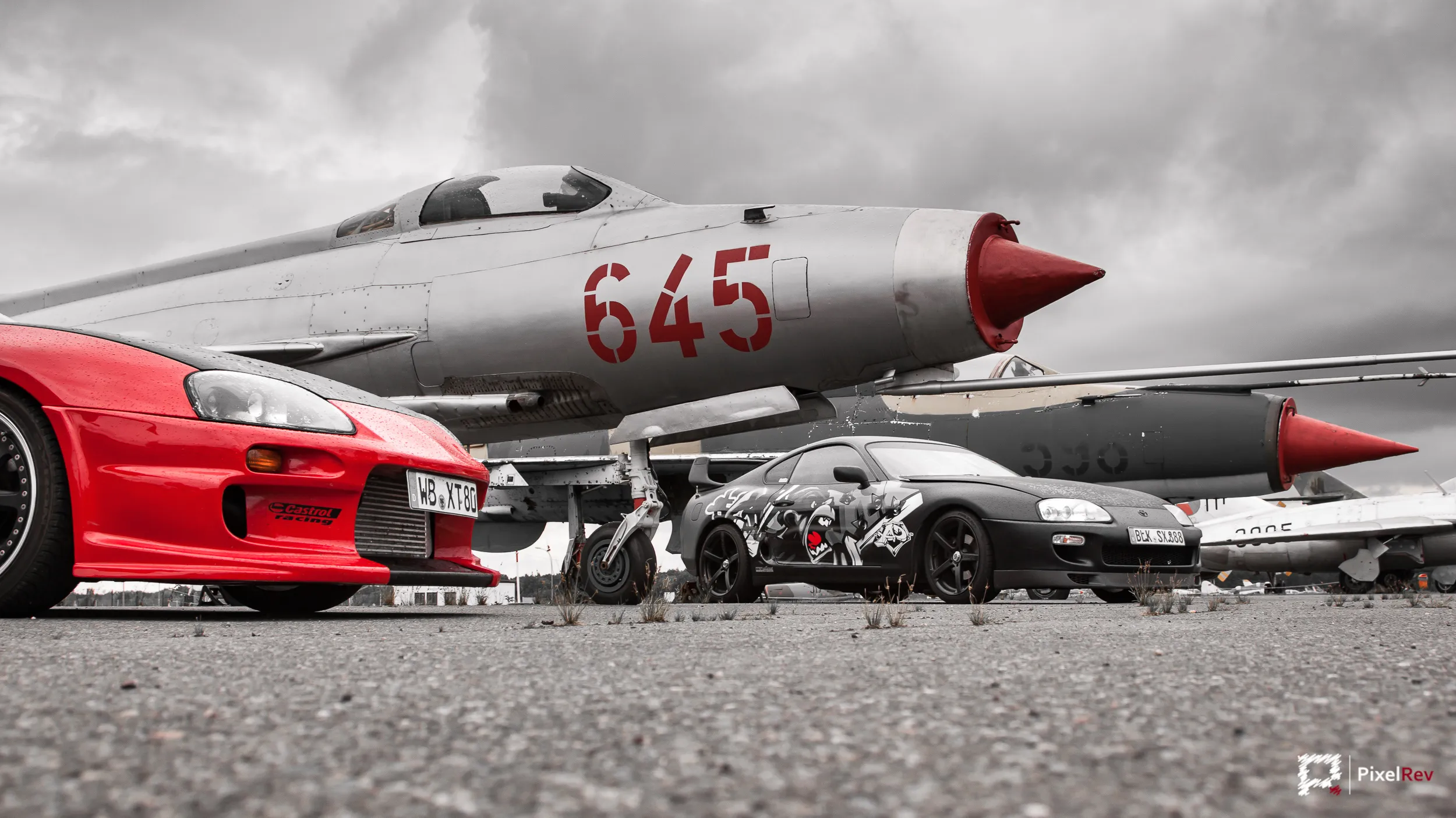Roter und schwarzer Toyota Supra vor der Nase eines MiG-21-Kampfjets