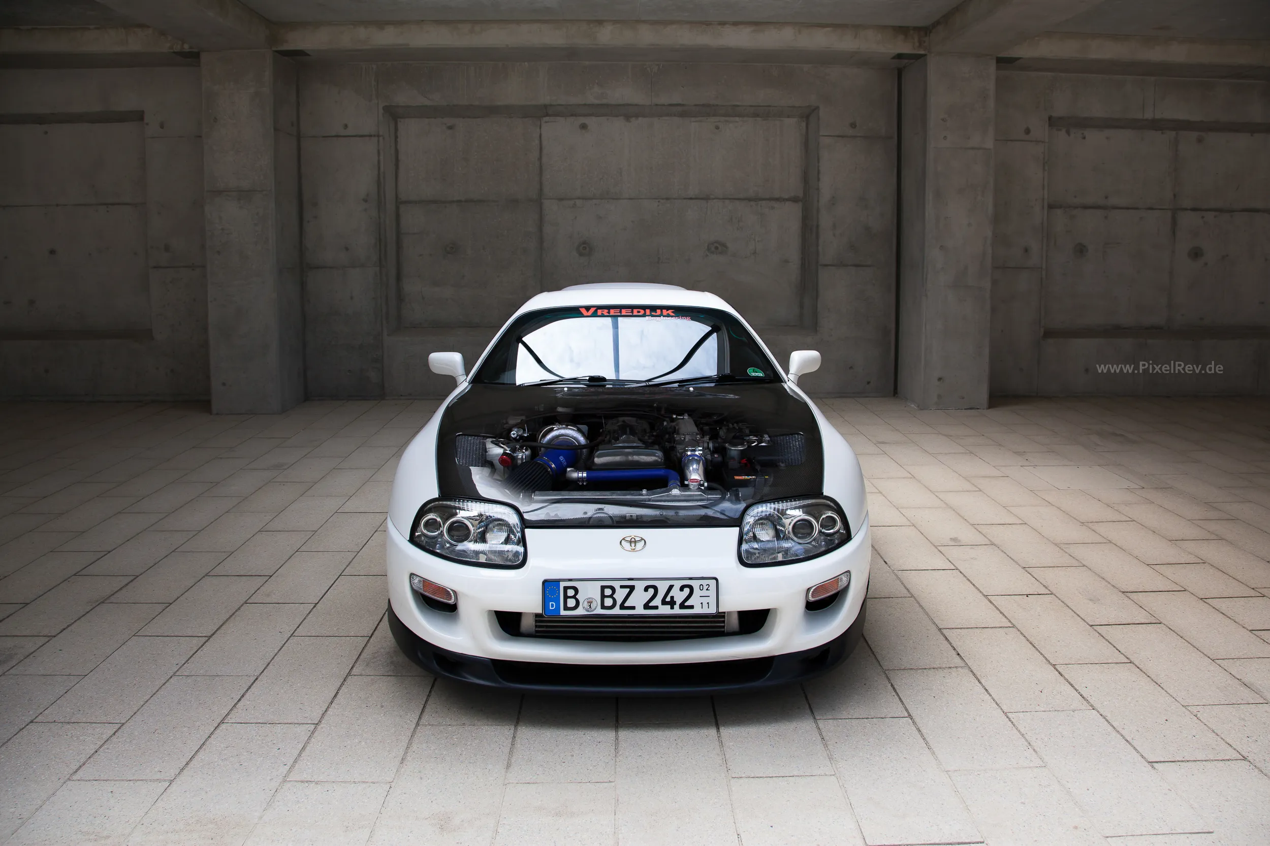Weißer Toyota Supra mit geöffneter Motorhaube in einer Halle