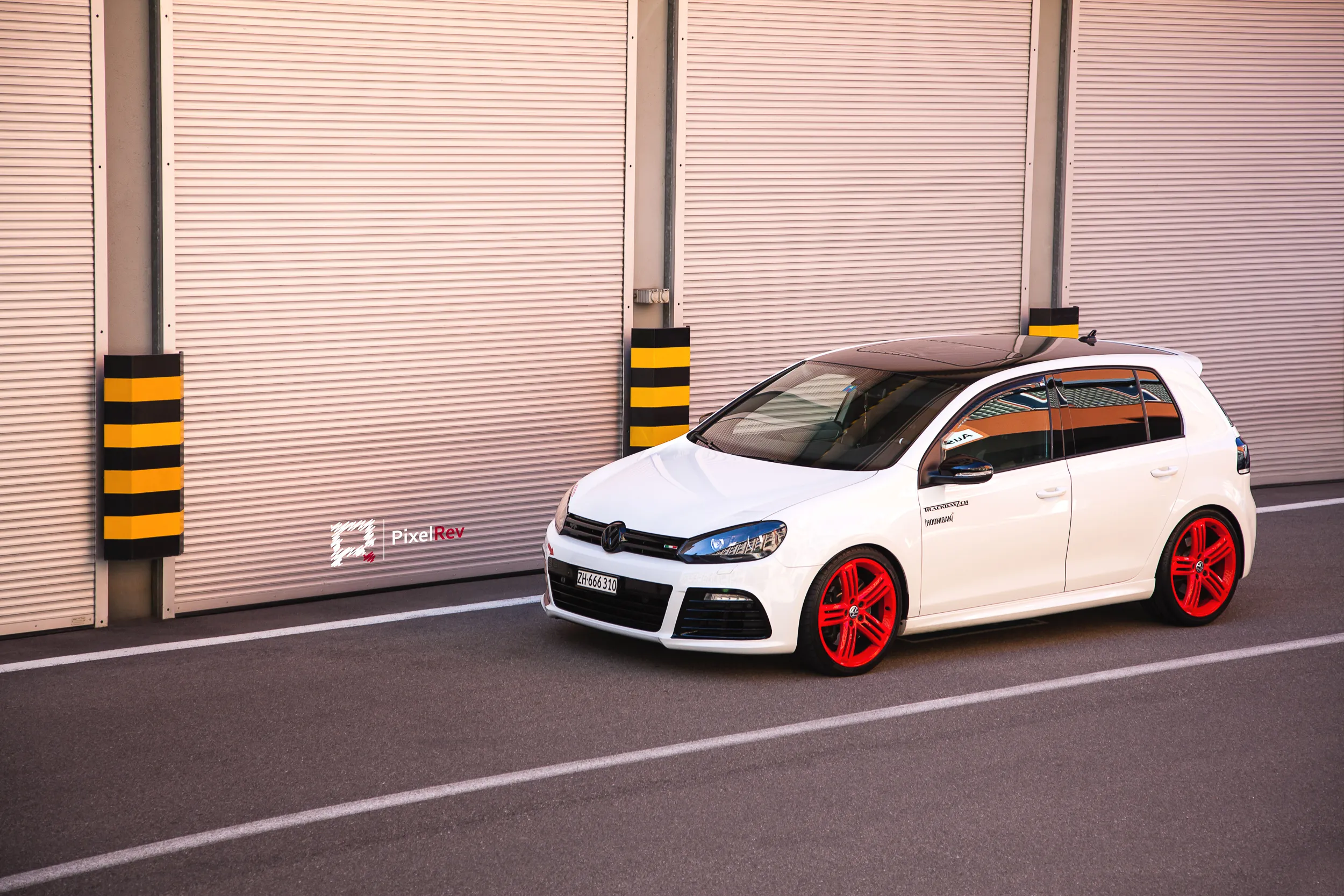 Weißer VW Golf R mit roten Felgen vor Rolltoren in Zürich